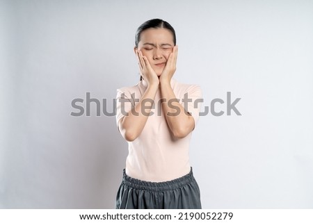 Asian woman was sick with toothache touching her cheek and standing isolated on white background.