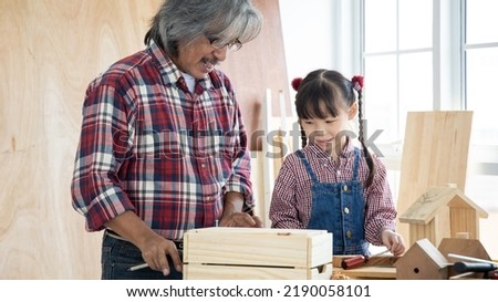 Asian little girl learning and playing with grandfather in wooden shop, concept for enhancing the development and thinking of children
