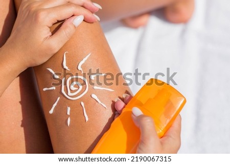 Sun protection cream for skin care. Close-up of a woman's legs applying sunscreen lotion before sunbathing. A beautiful dark-skinned woman puts cream on a tanned leg on a tropical beach. Royalty-Free Stock Photo #2190067315