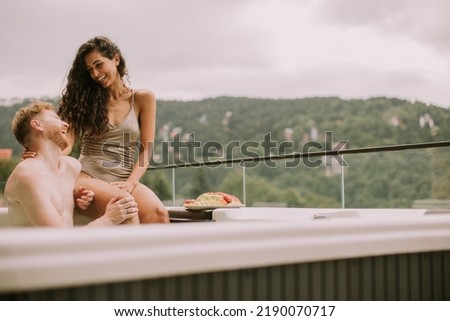Attractive young couple enjoying in outdoor hot tub on vacation