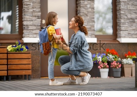 Parent and pupil of primary school going hand in hand. Woman and girl with backpack behind the back. Beginning of lessons. Royalty-Free Stock Photo #2190073407