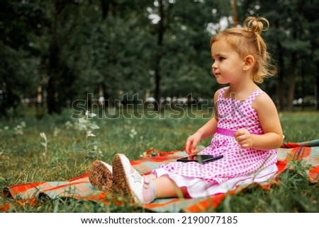 Little girl playing with a smartphone watching a cartoon in the Park