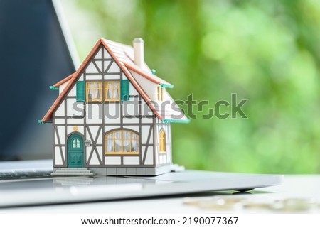 Online home auction, online property valuation and tax payment, financial concept : Model half-timbered house on a laptop computer keyboard, depicting a quick online real estate valuation estimate. Royalty-Free Stock Photo #2190077367