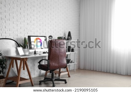 Photographer's workplace and shelving unit with equipment near white brick wall in studio