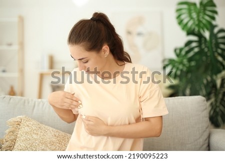 Young woman suffering from breast pain at home Royalty-Free Stock Photo #2190095223