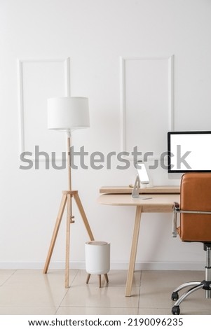 Modern workplace with computer and tablet in light office