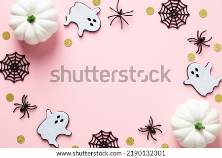 Happy Halloween holiday concept. Halloween decorations, pumpkins, spiders, webs, ghosts, confetti on pastel pink background.