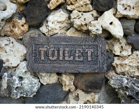 Toilet sign made of stone on a rock background