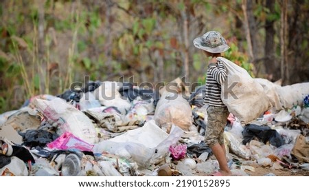 A poor Indian rag picker boy carrying a huge load of garbage collected during the day. Child labor in Indian cities due to poverty stricken children.