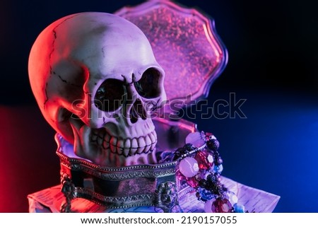 Human skull and treasure in copper vintage box on the map in neon red and blue light on dark background. Pirate treasure, treasure seekers concept . Selective focus, copy space