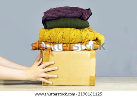 closeup woman hands holding carton box with used clothes for donation, collection and support of war victims, helping people, charity