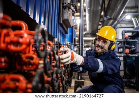 Industrial worker checking water pressure in city heating plant. Royalty-Free Stock Photo #2190164727