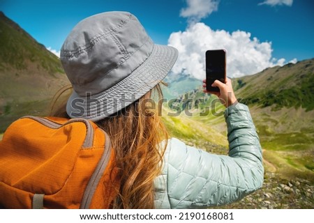 The girl is photographed on the phone picturesque views of mountains, forests and fluffy clouds, on a hike