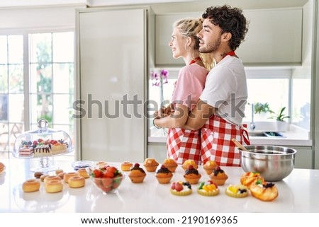 Couple of wife and husband cooking pastries at the kitchen looking to side, relax profile pose with natural face with confident smile. 