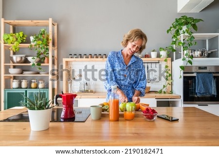Beautiful mature senior woman at home, domestic life and leisure moments - 50-60 years old pretty female adult cooking healthy food at home in the kitchen for diet Royalty-Free Stock Photo #2190182471
