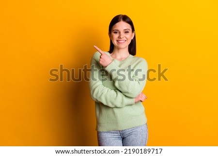 Photo of young pretty woman indicate finger empty space recommend suggest ad isolated over yellow color background.