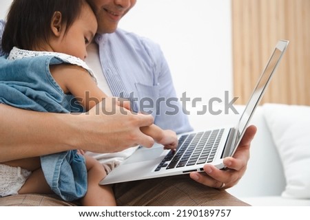Happy father and little daughter laughing watching funny video using laptop, cheerful dad and child girl having fun with cartoons online at home
