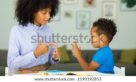 A smart boy counts on his fingers, studies with a private teacher in the office, a child learns numbers and how to count, sits at a table with a tutor Royalty-Free Stock Photo #2190192853