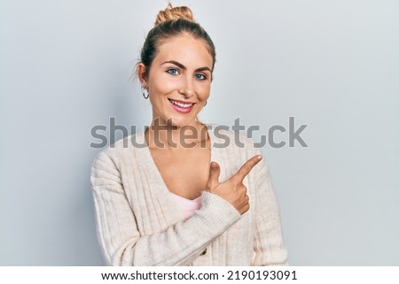 Young caucasian woman wearing casual clothes smiling cheerful pointing with hand and finger up to the side 