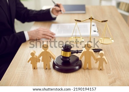 Figures of family are separated by judge's gavel, which symbolizes divorce case and custody of child. Close up of wooden figurines of people on background of judges and scales of justice. Royalty-Free Stock Photo #2190194157