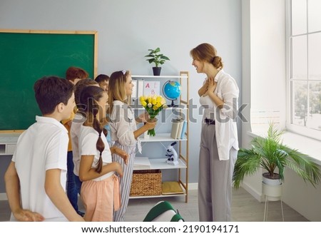 Little grateful children teenagers give bouquet of flowers to woman elementary school tutor as token appreciation or as gift at Teacher Appreciation Week stand in classroom. Education, back to Royalty-Free Stock Photo #2190194171