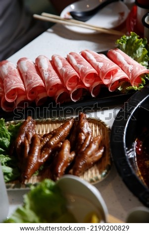 A view of a plate of raw beef slices, part of a hot pot meal.