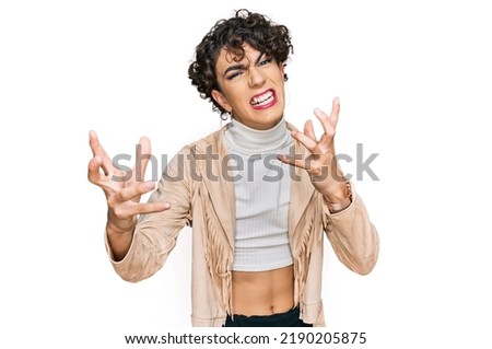 Handsome man wearing make up and woman clothes shouting frustrated with rage, hands trying to strangle, yelling mad 