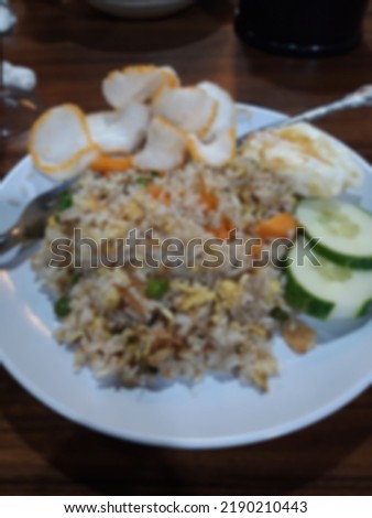 Defocused picture of a plate of friend rice with vegetables toppings and a fried egg