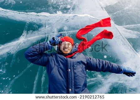 Travel winter Lake Baikal, smile man tourist in red cap lie on ice.