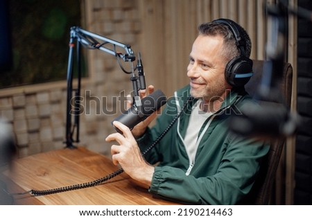 Portrait of mature radio host speaking in microphone while moderating a live show