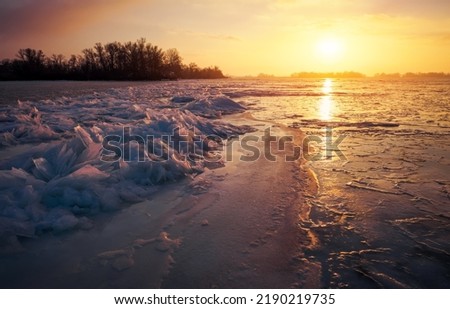 Winter landscape with sunset sky and frozen sea coast. Daybreak