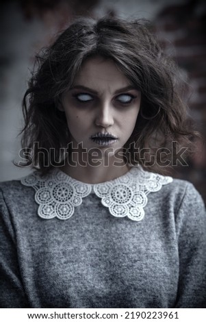 Portrait of an angry ghost girl with colorless eyes and black hair staring intently at the camera. Horror film, thriller. Halloween. Royalty-Free Stock Photo #2190223961