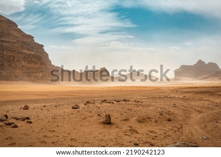 The wind raises the dust in Wadi Rum, Sahara or Arabian desert Royalty-Free Stock Photo #2190242123