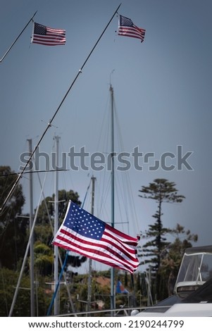 Three flags flying from boats, blowing in the wind, at Glorietta Bay in Coronado, California. Royalty-Free Stock Photo #2190244799