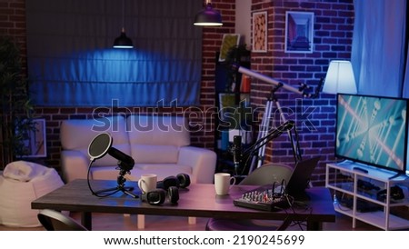 Nobody in podcast production studio with professional microphone and headphones for streaming interview on internet radio. Empty desk with streaming equipment to broadcast live show on social media.