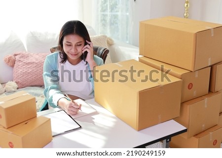 Attractive happy asian pregnant woman sitting and using mobile smart phone and writing order for customer with tablet. Expectant mother preparing and working for baby birth during pregnancy concept.