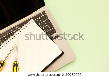 screwdrivers, laptop and notebook on green background