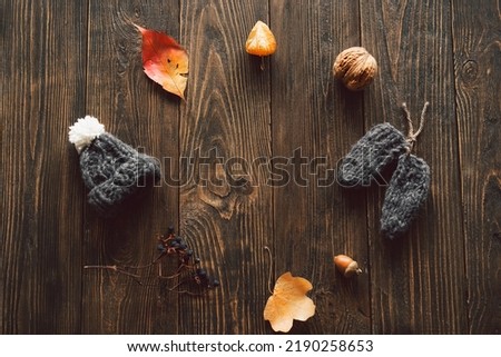 Autumn composition. Autumn dried leaves, knitted little hat on wood background. Flat lay, top view