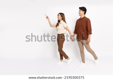 Young Asian couple walking and pointing to empty copy space isolated on white background, Full body composition Royalty-Free Stock Photo #2190300375