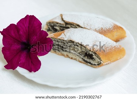 Poppy seed cake lies on a plate decorated with a live flower