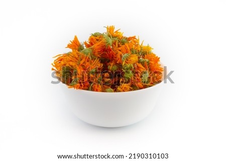 Dried orange calendula flowers in a ceramic white bowl isolated on white background. Pot marigold is medical herbs.