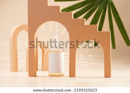 A mock-up of a transparent cosmetics bottle with yellow liquid and white label in peach colored arched doors for cosmetics photography on beige colored background