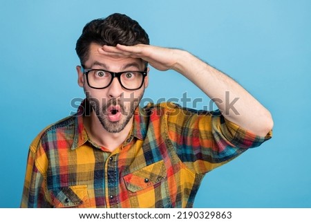 Photo of impressed brunet guy look camera wear eyewear yellow shirt isolated on blue color background