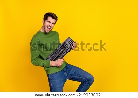 Photo of funny funky guy dressed green pullover playing keyboard empty space isolated yellow color background