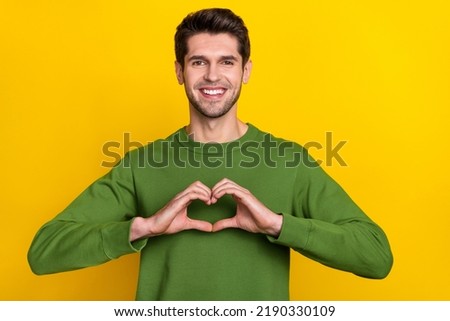 Photo of pretty charming guy dressed green pullover showing arms heart isolated yellow color background