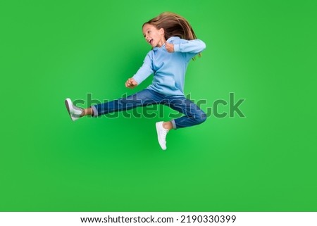 Full body photo of energetic small girl jump practicing martial arts fan dressed trendy blue sportswear isolated on green color background Royalty-Free Stock Photo #2190330399
