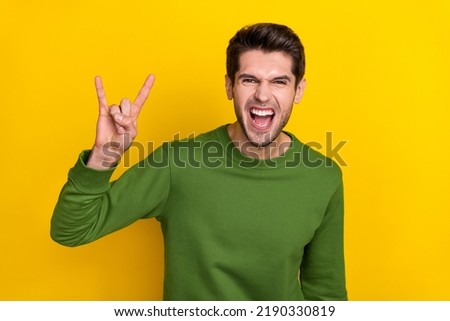 Photo of cool funny guy wear green sweater showing hard rock sign isolated yellow color background
