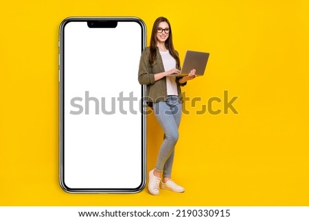 Full body photo of positive charming business lady working in netbook promote new phone isolated on yellow color background