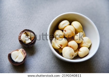 Delicious peeled Macadamia nut in a salad bowl on a gray background. The kernels of a delicious Macadamia nut close-up. Healthy meal.