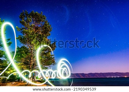 Freezlight photos style. Beautiful night landscape - a tree on the seashore, golden sand of the sea and a bright glowing sky